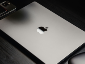 Top view of modern silver Apple MacBook and iPhone on a black wood surface