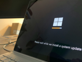 Laptop displaying a Windows system update screen with a progress bar and the text: 'Please wait while we install a system update'
