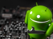 The Bugdroid holding a wrench and standing on a motherboard.