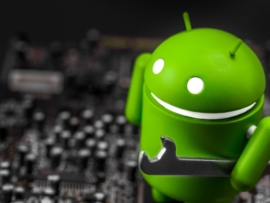 The Bugdroid holding a wrench and standing on a motherboard.