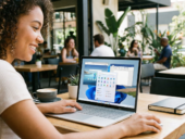 Smiling woman using a Microsoft Surface Laptop with Windows 11 in a modern cafe.