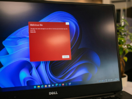 A laptop with a red notification about a malicious file.