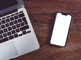 MacBook and iphone placed on a wooden surface.