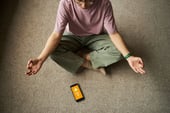 A person meditating while a health app is open in a smartphone