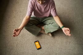 A person meditating while a health app is open in a smartphone