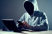 An unknown hooded person hacking a smartphone.