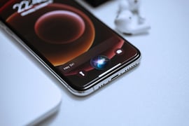Smartphone on white table with Siri AI.