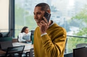 A man inside the office answering a call using a Motorola smartphone.