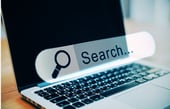 Laptop with a large 'Search' bar icon, illustrating web browsing and data retrieval concepts.