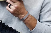 WHOOP 4.0 fitness wearable on a wrist, featuring a grey band with orange trim and a black athletic ring.