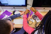 Young girls holding circuitboards and coding.