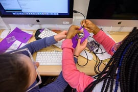 Young girls holding circuitboards and coding.