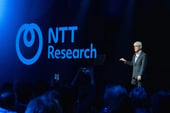 A person speaking in front of an audience with the NTT Research logo in the backdrop.