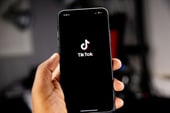 A person holding a phone with TikTok app on screen.