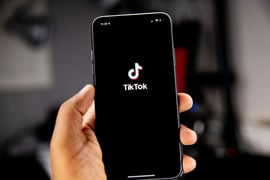 A person holding a phone with TikTok app on screen.
