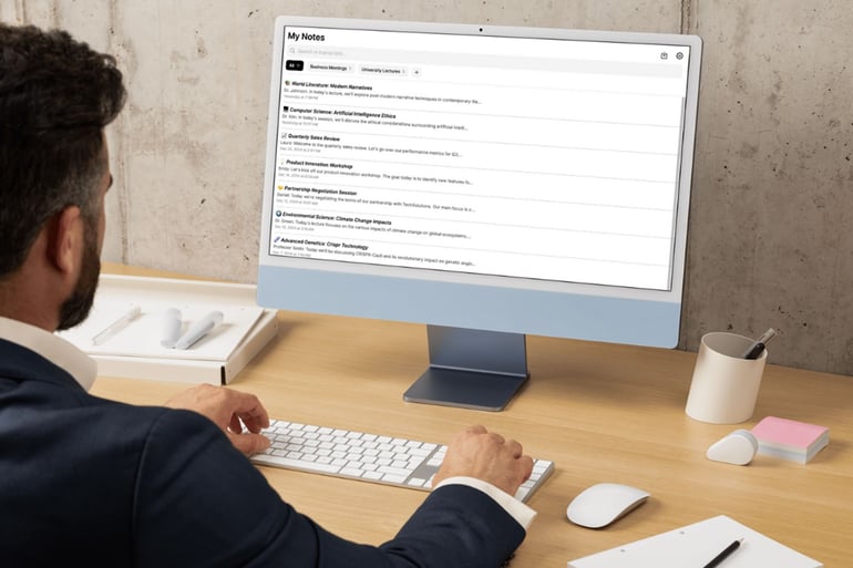 A businessman typing on a keyboard at a wooden desk with an iMac displaying the My Notes app interface.